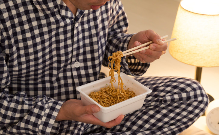 カップ焼きそばを食べている男性